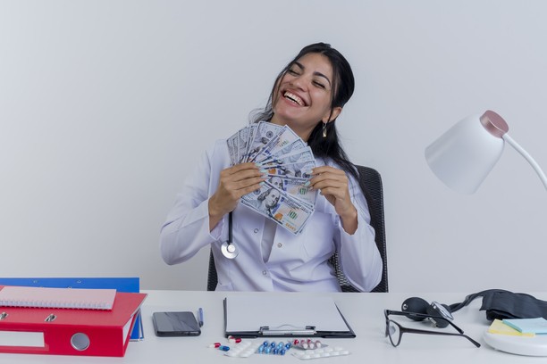 Happy doctor holding a fan of US dollar bills.