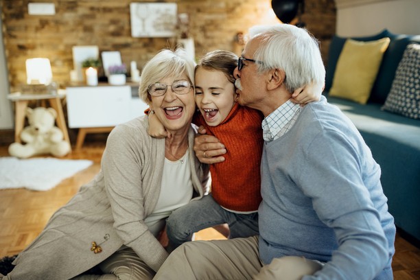 A smiling little girl hugged and kissed by her grandparents.