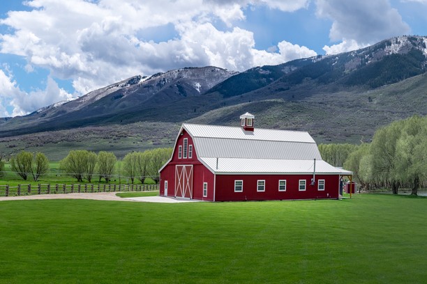 Red barn and snowy mountains in a green field