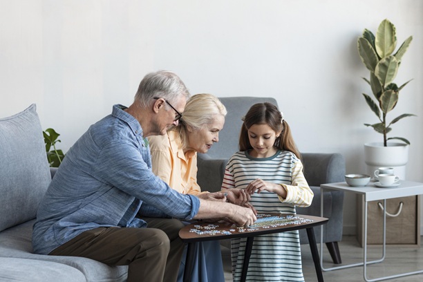 Grandparents playing puzzle with granddaughter at home