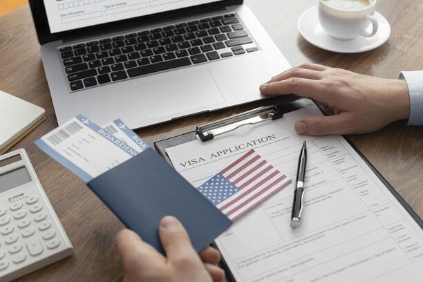 A person filling out a visa application form at a desk.